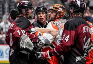 Players and a referee engaged in a scuffle during a National Lacrosse League game.