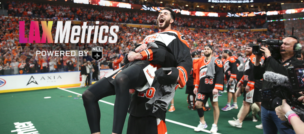 A celebrating lacrosse player lifts a teammate on the field, surrounded by an enthusiastic crowd.