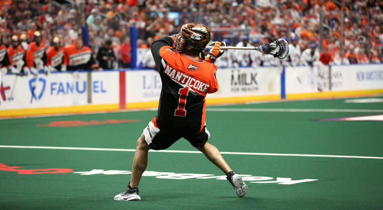 Lacrosse player in an orange and black jersey shooting a ball on the field.