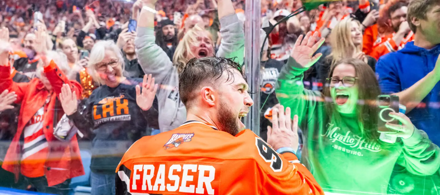 Hockey player Fraser celebrating with cheering fans behind glass barrier
