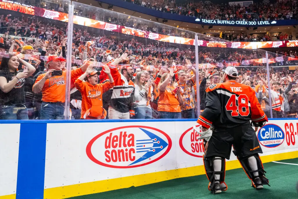 Vinc #48 facing cheering fans behind glass, "Bandits" logos visible