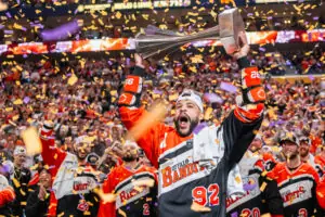 Celebratory scene with an athlete in a Buffalo Bandits jersey holding a trophy amid falling confetti