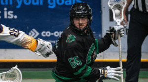 Jaxon-Fridge.png playing lacrosse, wearing black and green jersey, holding stick