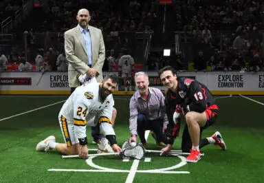 DEV_2652-scaled.jpg shows a ceremonial lacrosse face-off with two players and two officials on a field