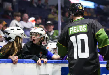 Hockey player Fields interacts with excited young fans wearing helmets