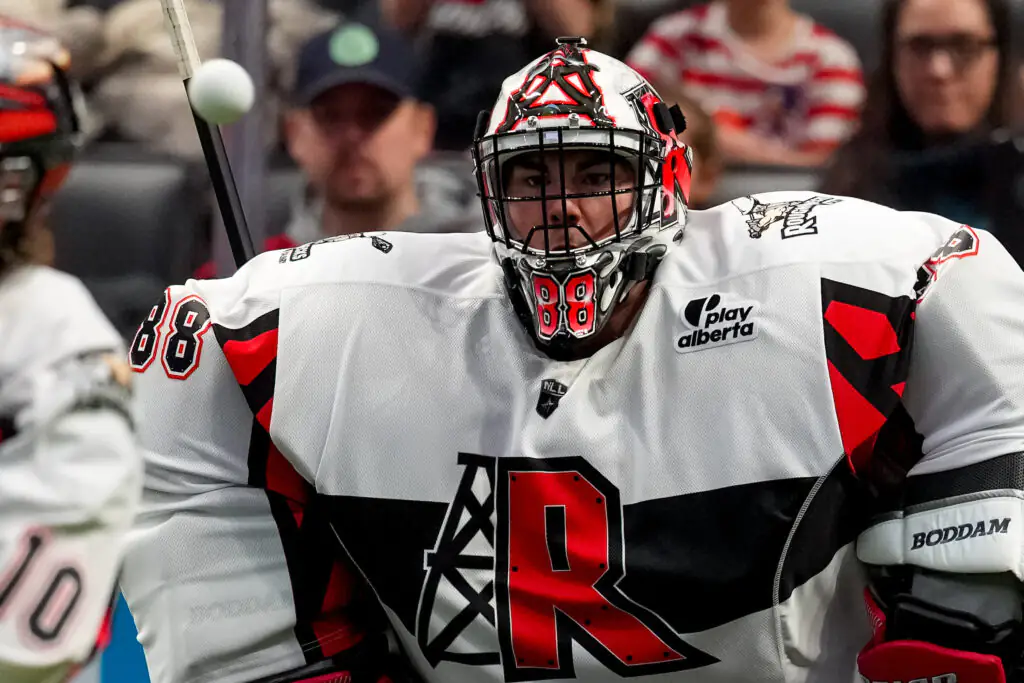 Hockey goalie in white jersey with number 88, focused during game