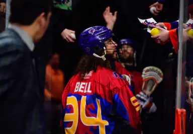 Player wearing a "Bell 94" jersey interacts with fans, receiving items for autographs